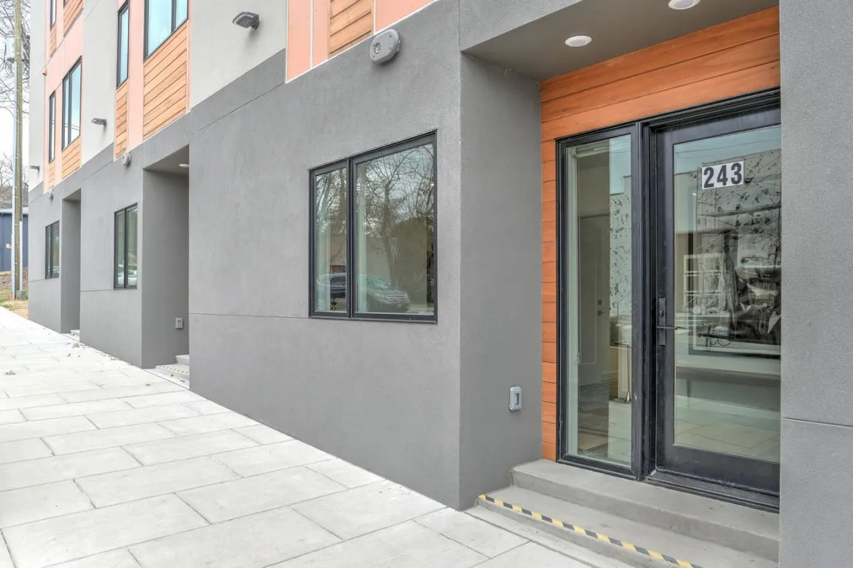 The exterior entrance of the property, showcasing a stylish door, large windows, and wood accents. The scene is welcoming, setting the stage for a positive first impression as guests arrive.