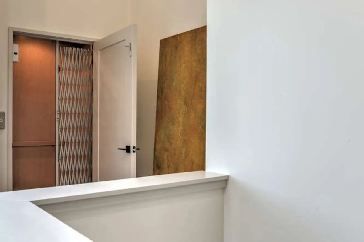 A contemporary setting with clean architectural lines, a textured feature wall, and a sleek elevator door. The space feels inviting and modern, emphasizing anticipation and movement throughout the home.