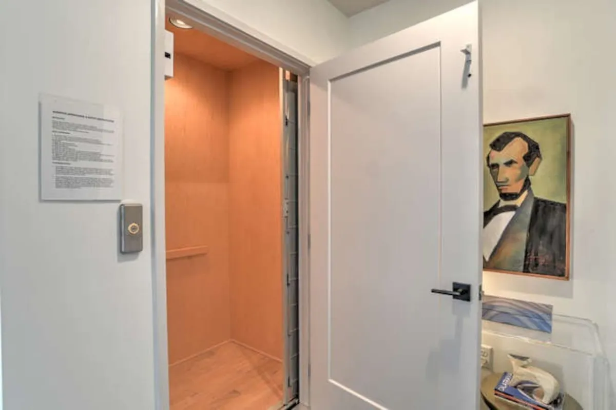 A practical and sophisticated interior scene focused on a private elevator, with a portrait of Abraham Lincoln adding a unique, historic touch. The space is clearly functional and modern, highlighting the elevator as a key amenity for accessing all floors.